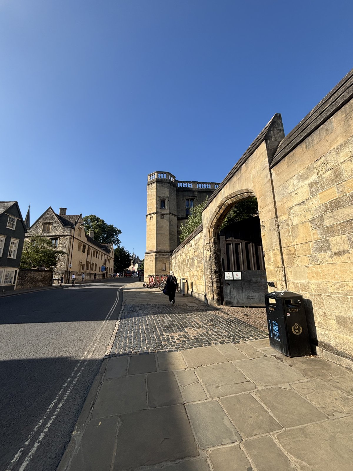 Una calle empedrada junto a la muralla de uno de los colleges